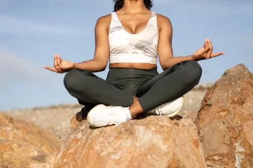 a woman meditating on a rock