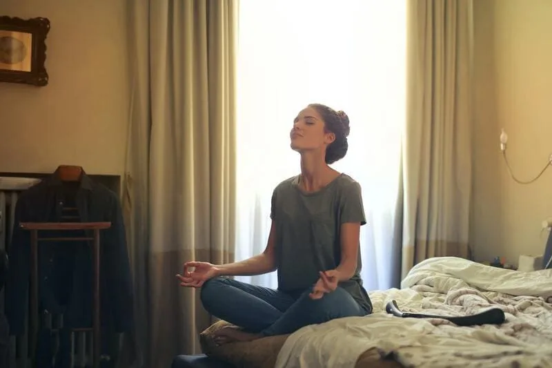a woman meditating on a bed