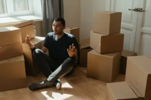 A man meditating amid the moving boxes, adjusting to a new environment.
